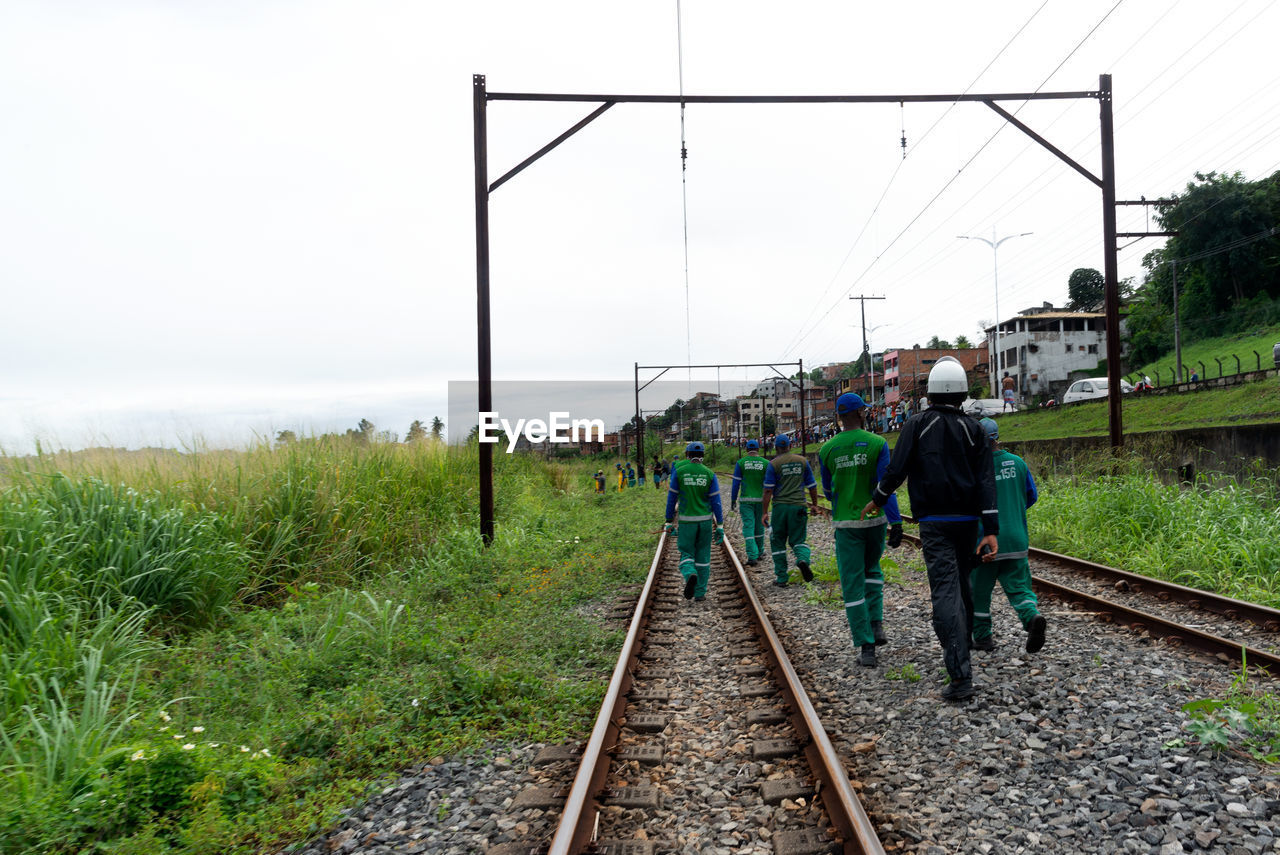 track, railroad track, rail transportation, transport, transportation, nature, sky, vehicle, railway, mode of transportation, group of people, men, travel, day, full length, plant, adult, train, rolling stock, outdoors, land