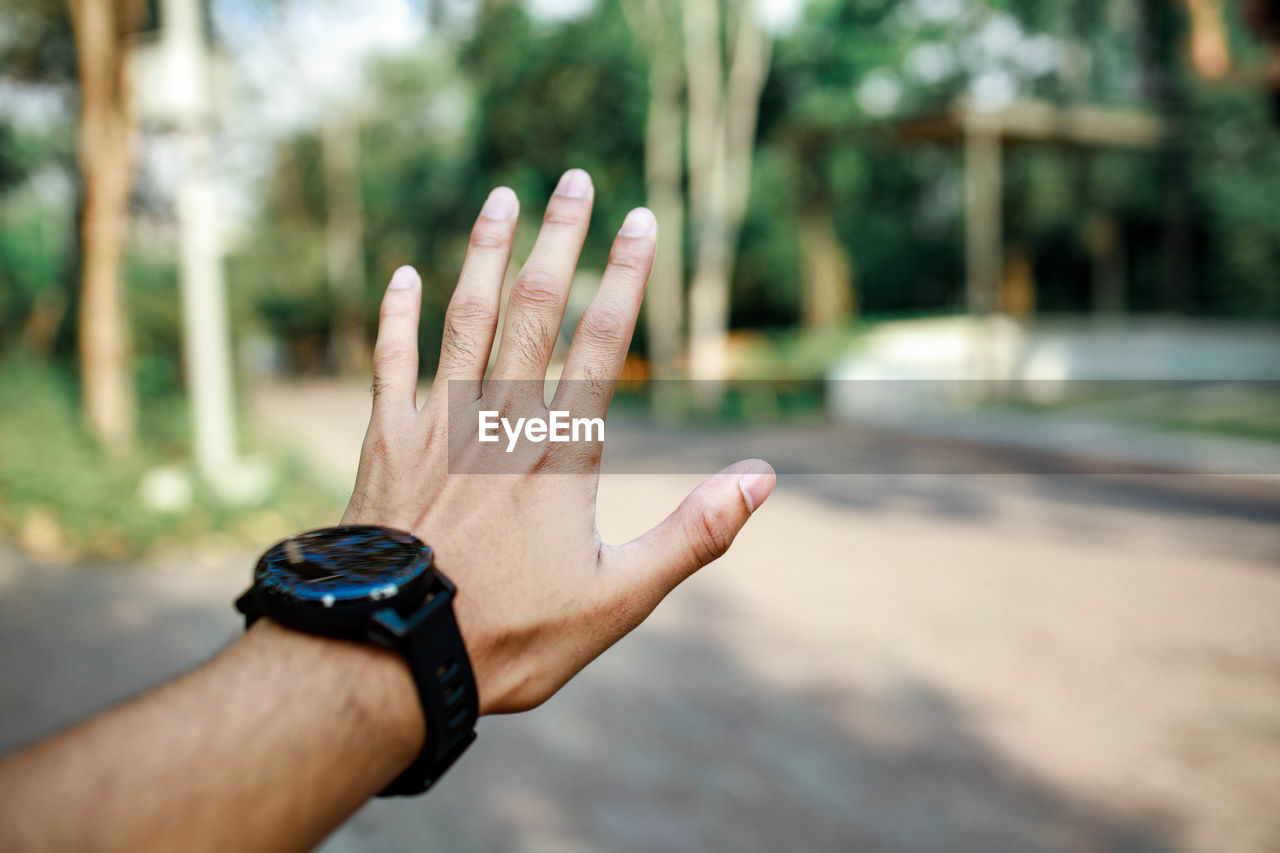Cropped image of hand with wristwatch against blurred background