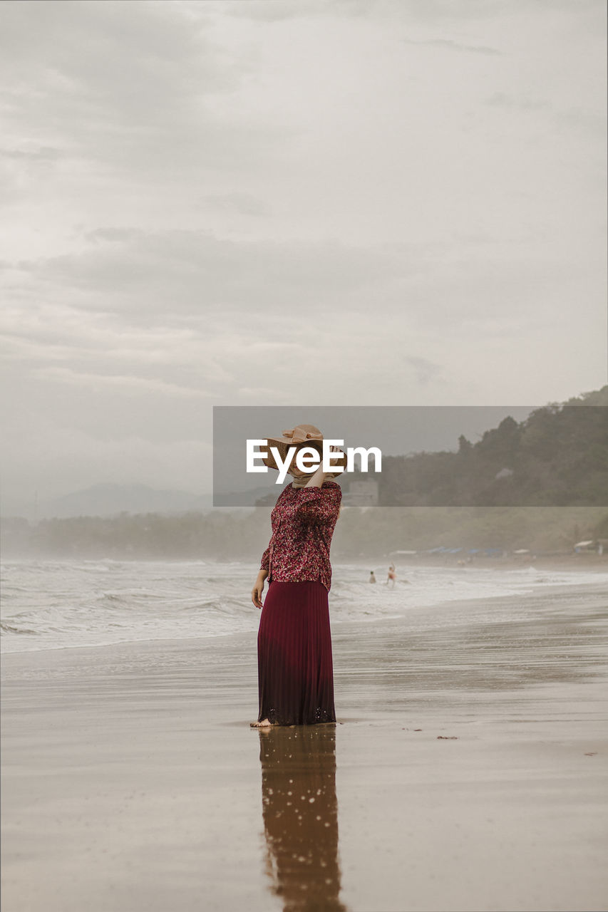 WOMAN STANDING ON BEACH