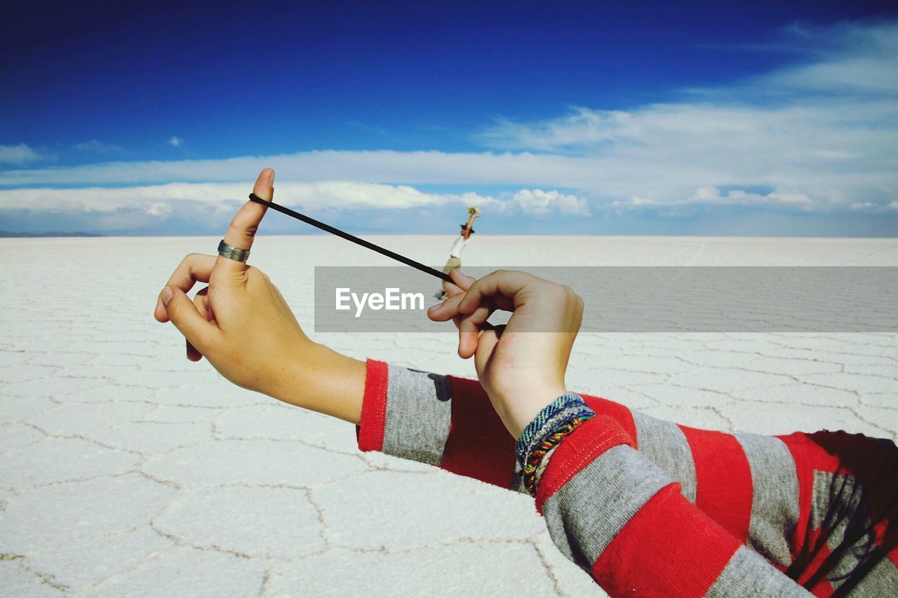 Optical illusion of woman aiming slingshot with man at salar de uyuni