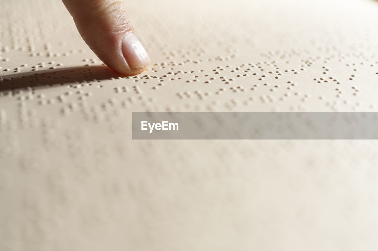 A finger following the reading of a page written in the braille alphabet, the tactile reading system