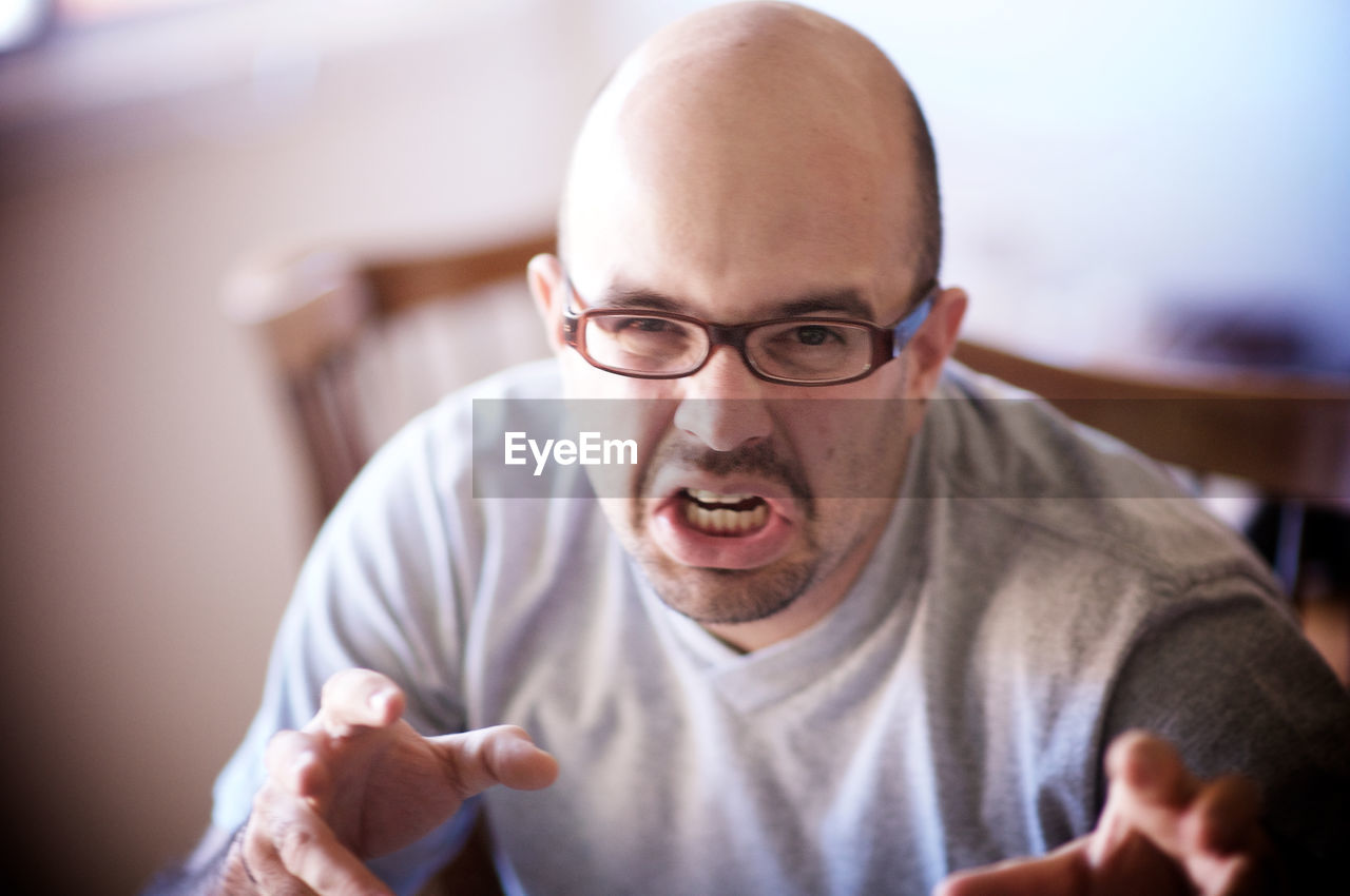 Portrait of man gesturing while making face at home