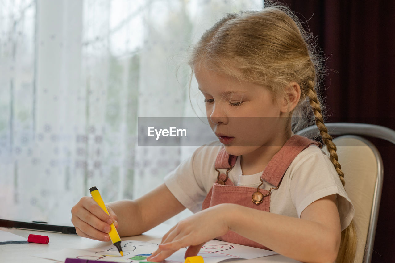 Girl drawing over paper on table