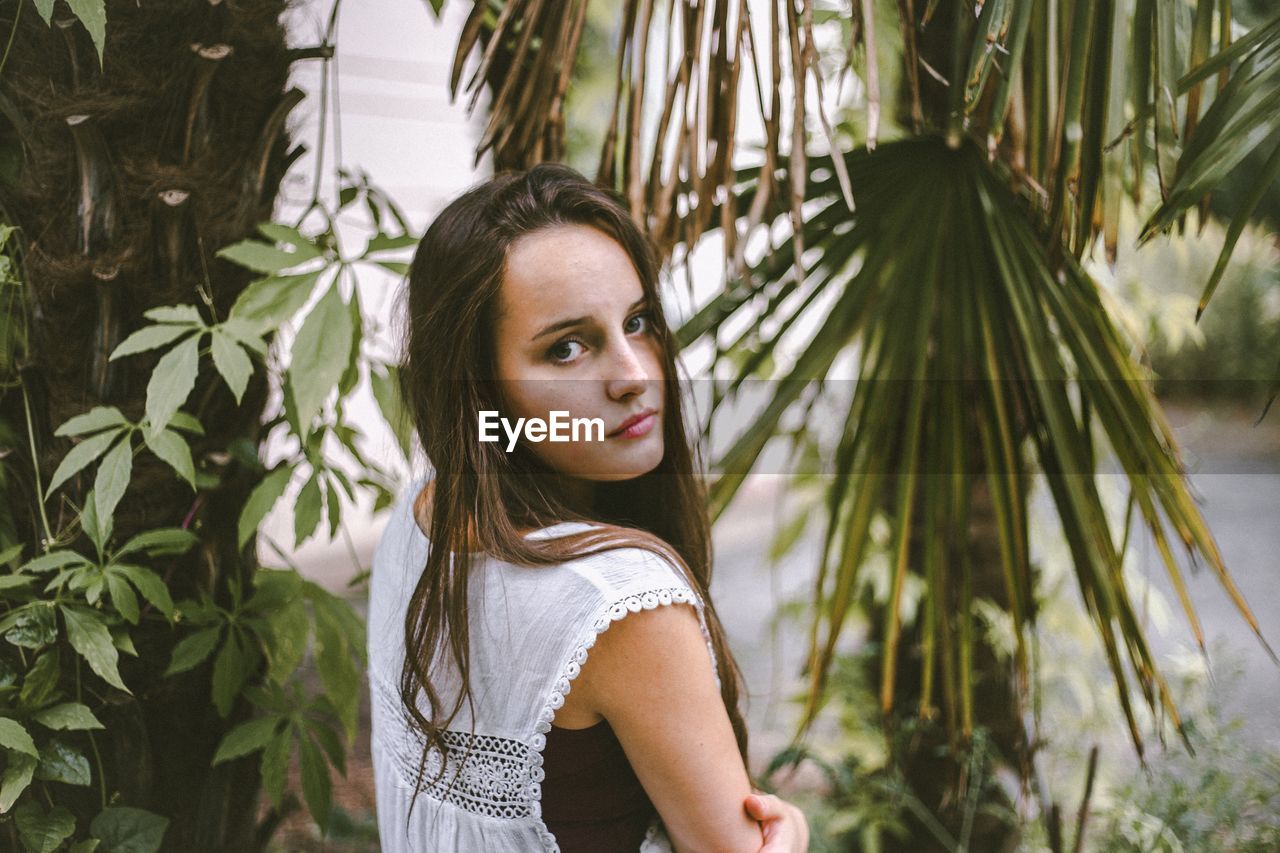 PORTRAIT OF WOMAN STANDING BY TREE