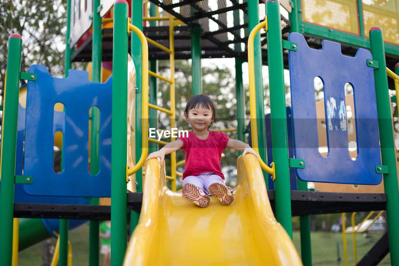 Low angle view of girl playing on slide at playground