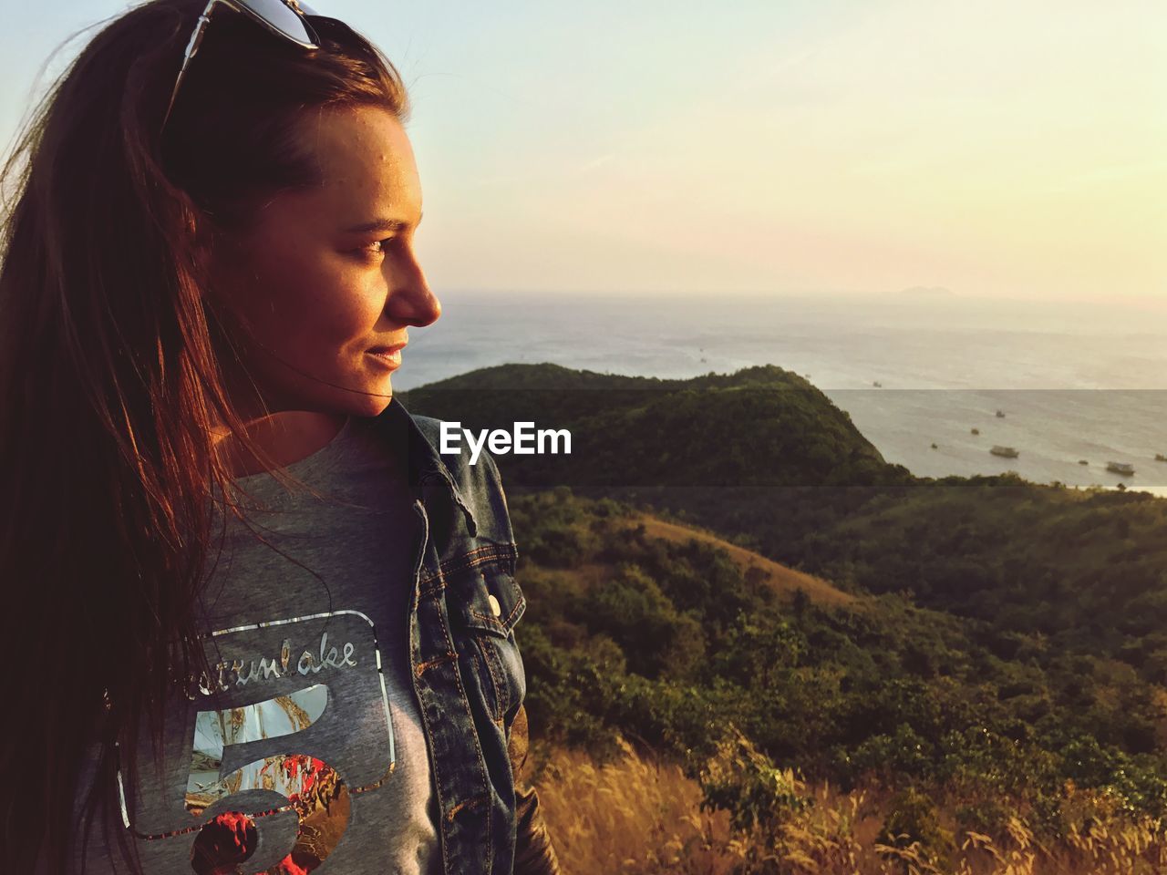 Close-up of woman looking at sea against sky during sunset