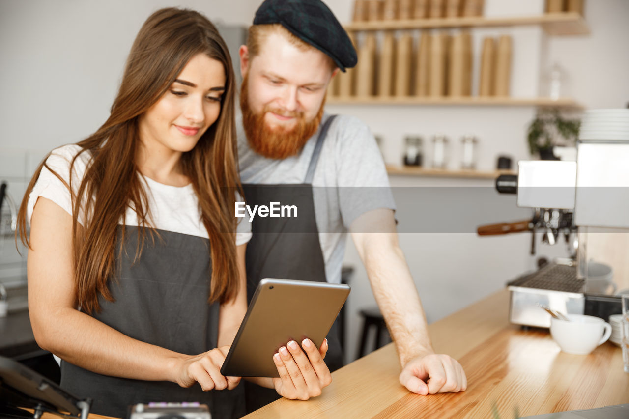 portrait of smiling young woman using digital tablet while sitting at home