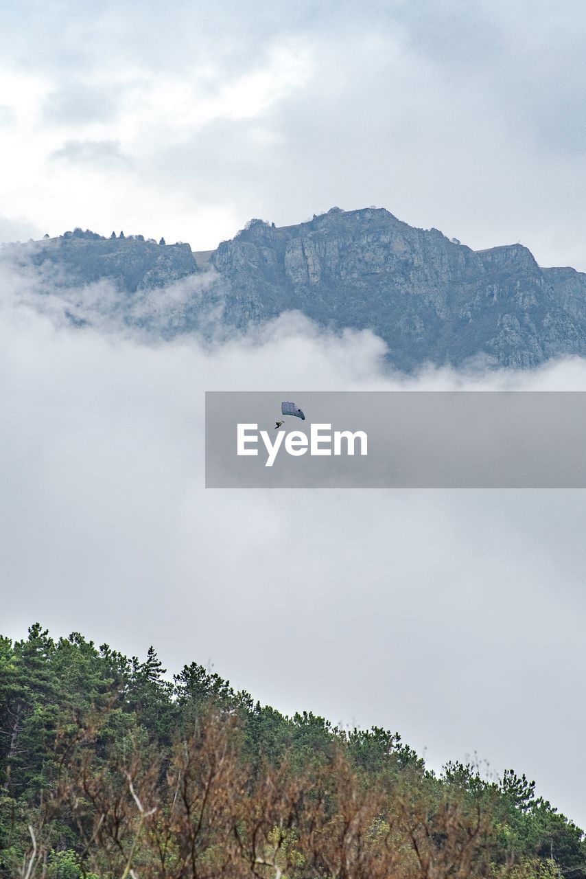 LOW ANGLE VIEW OF BIRD FLYING OVER MOUNTAIN AGAINST SKY