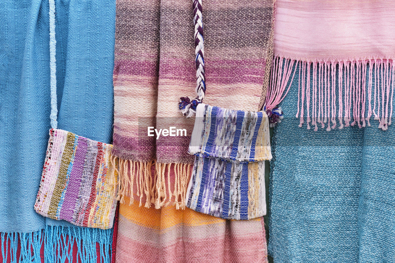 Colorful woven scarves and bags as an abstract textile background.