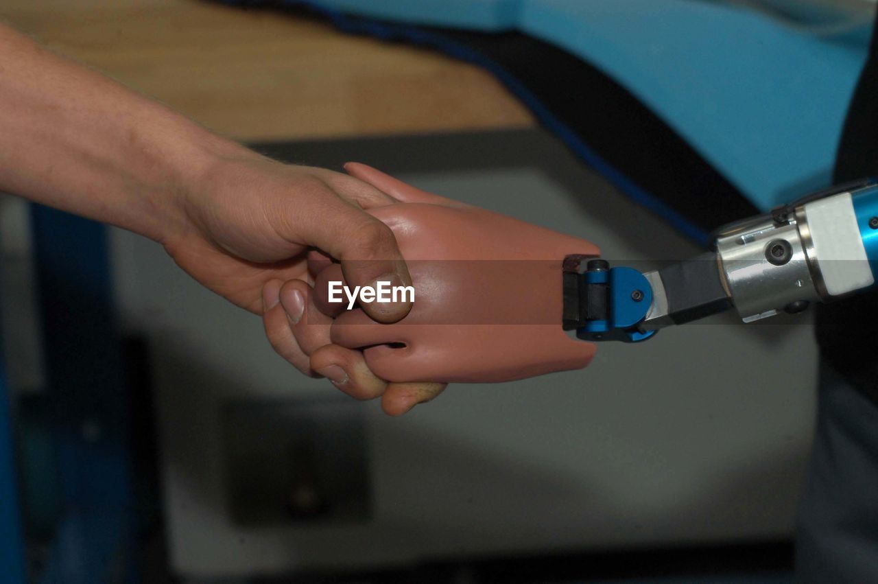 Cropped image of man doing handshake with robotic arm