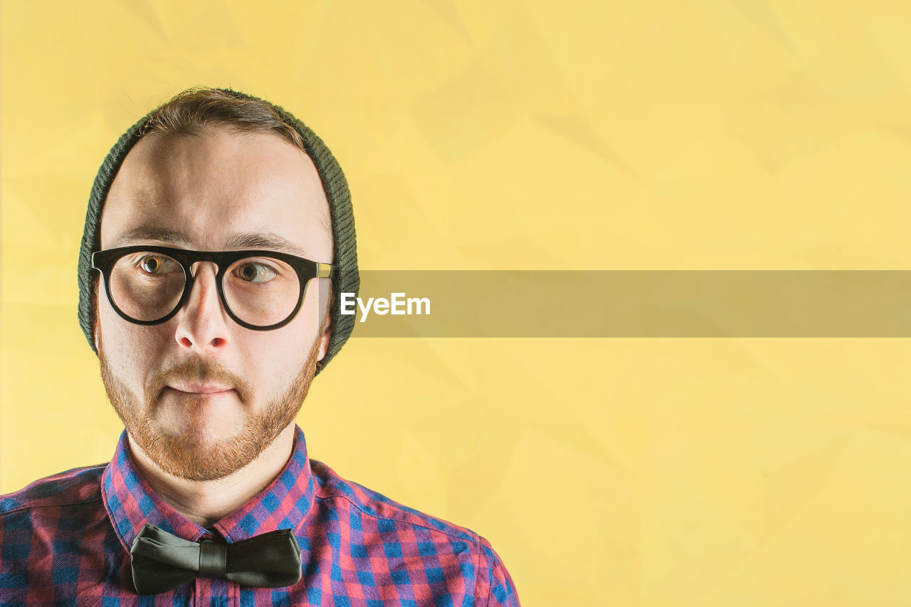 Close-up of young man against yellow background