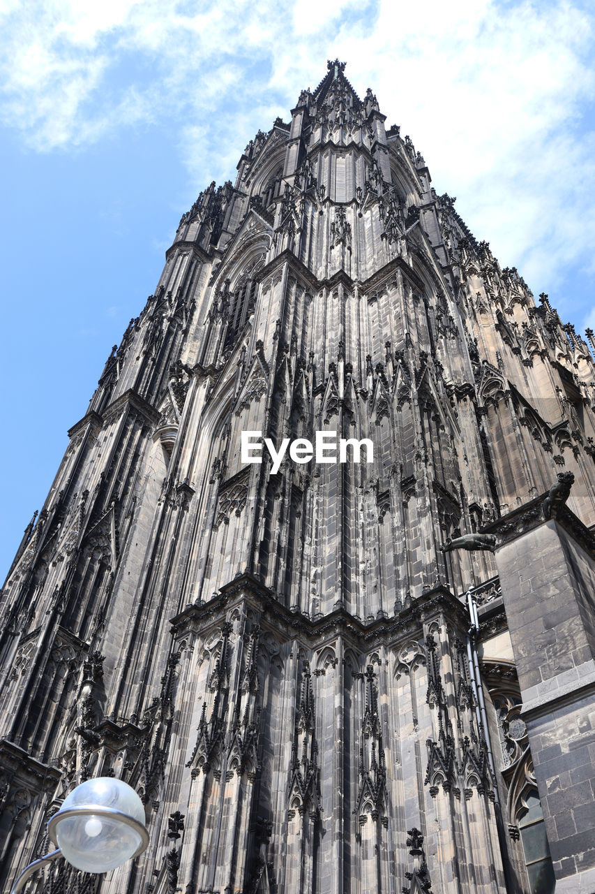 Cologne cathedral seen from below with blue sky and cloud behind