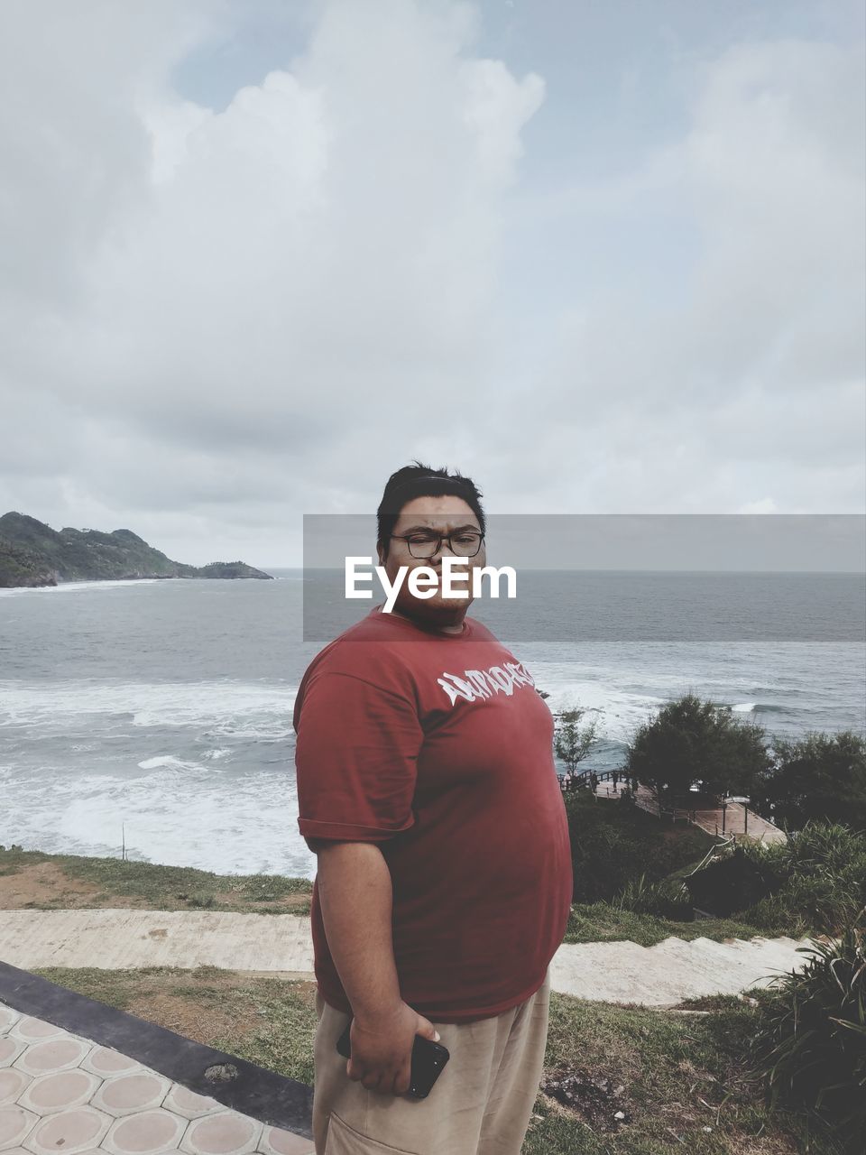 FULL LENGTH OF SMILING MAN STANDING ON BEACH
