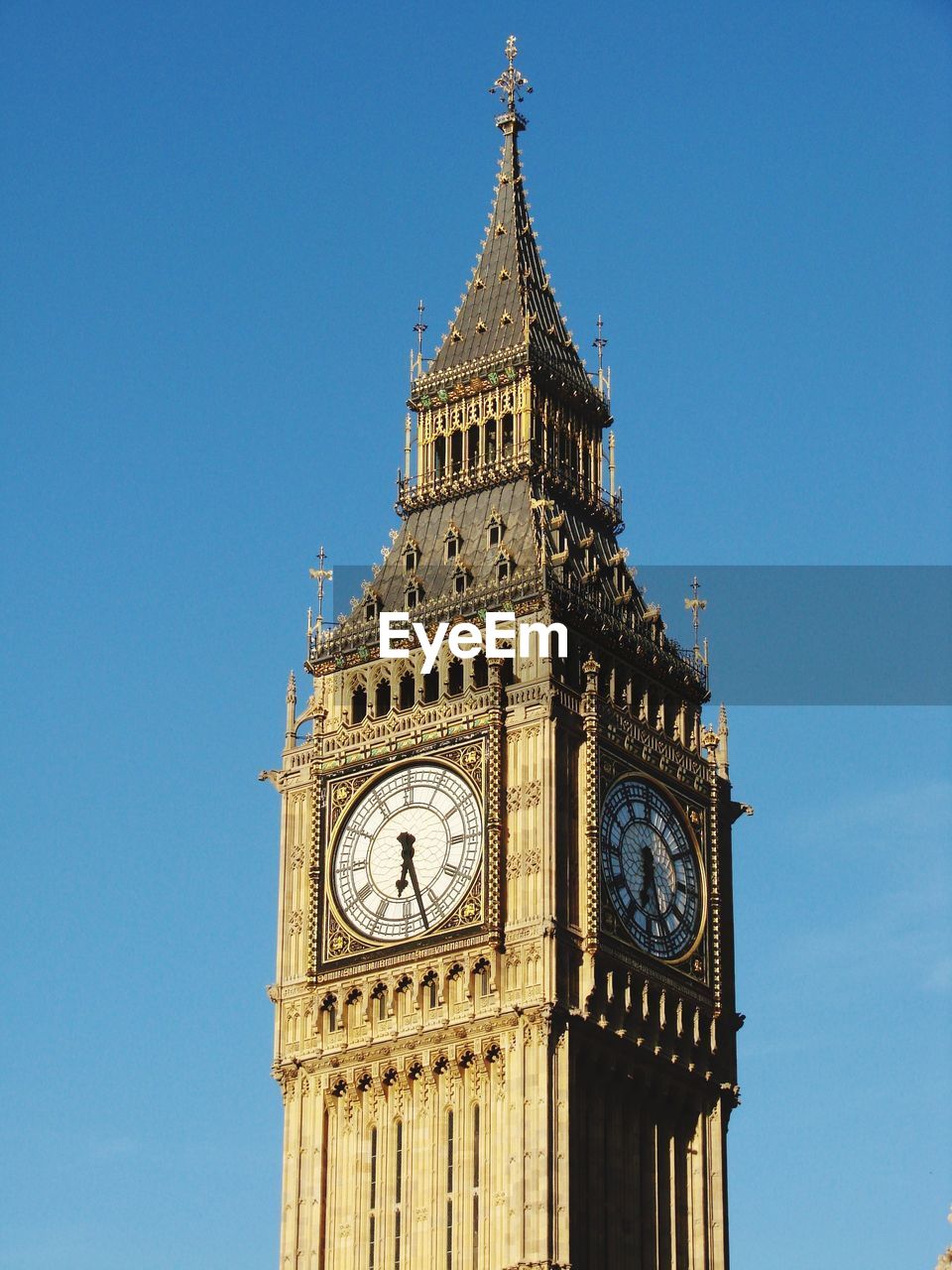 Low angle view of clock tower against clear blue sky