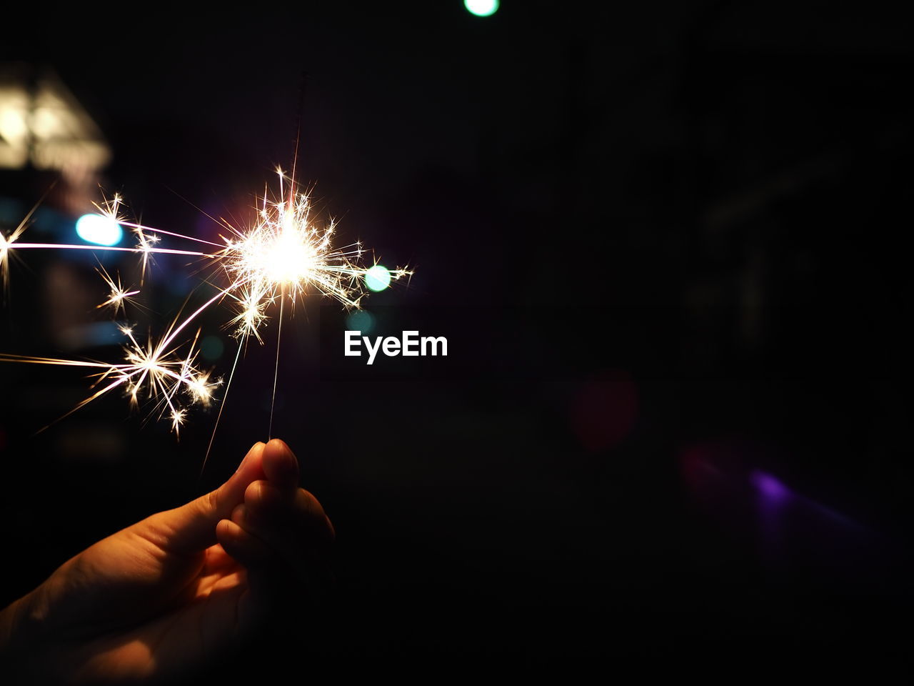 PERSON HAND HOLDING ILLUMINATED FIREWORK DISPLAY