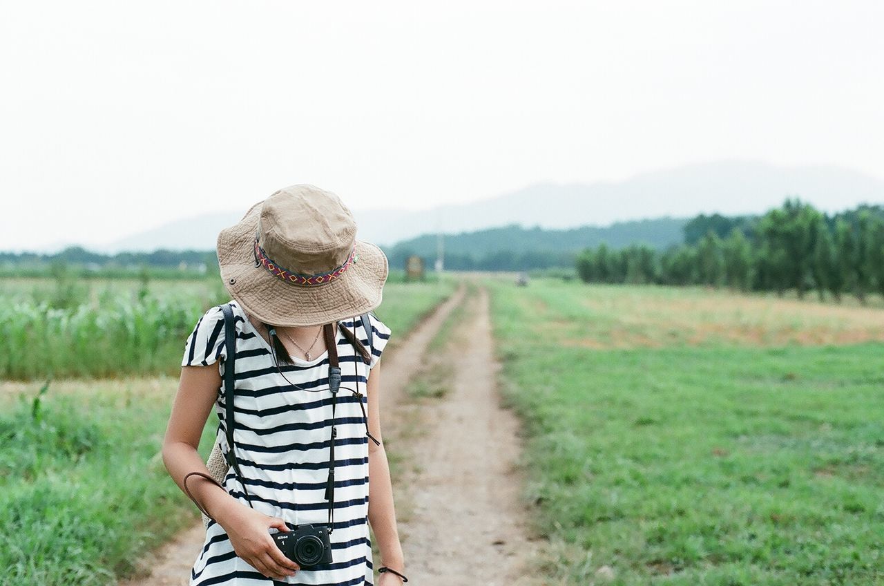 Woman wearing sun hat while photographing on field