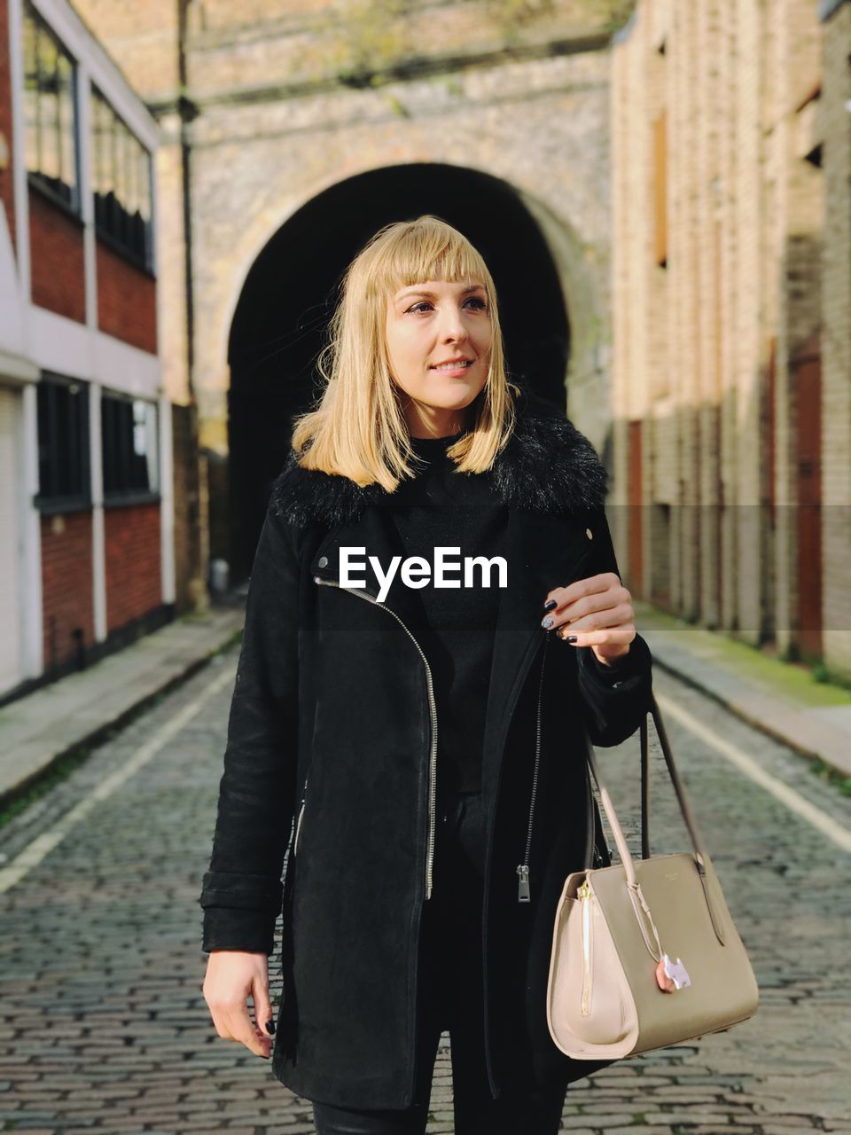 Smiling woman standing on street against building in city