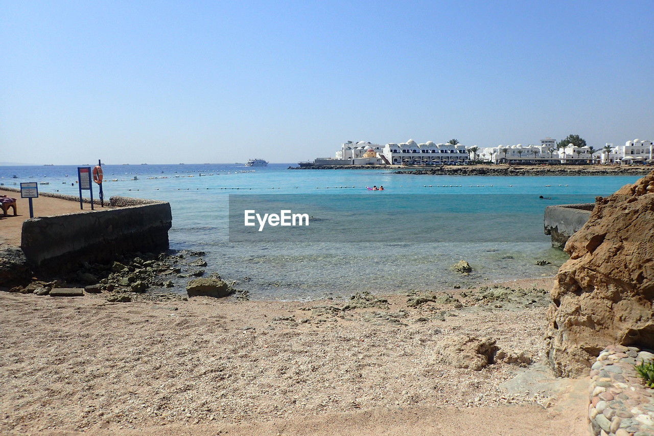 water, sea, beach, land, sky, shore, body of water, coast, nature, clear sky, ocean, vacation, travel destinations, sand, travel, nautical vessel, scenics - nature, transportation, holiday, trip, day, architecture, sunny, bay, beauty in nature, blue, tourism, coastline, mode of transportation, outdoors, tranquility, sunlight, built structure, horizon, tranquil scene, horizon over water, rock, building exterior, idyllic, city