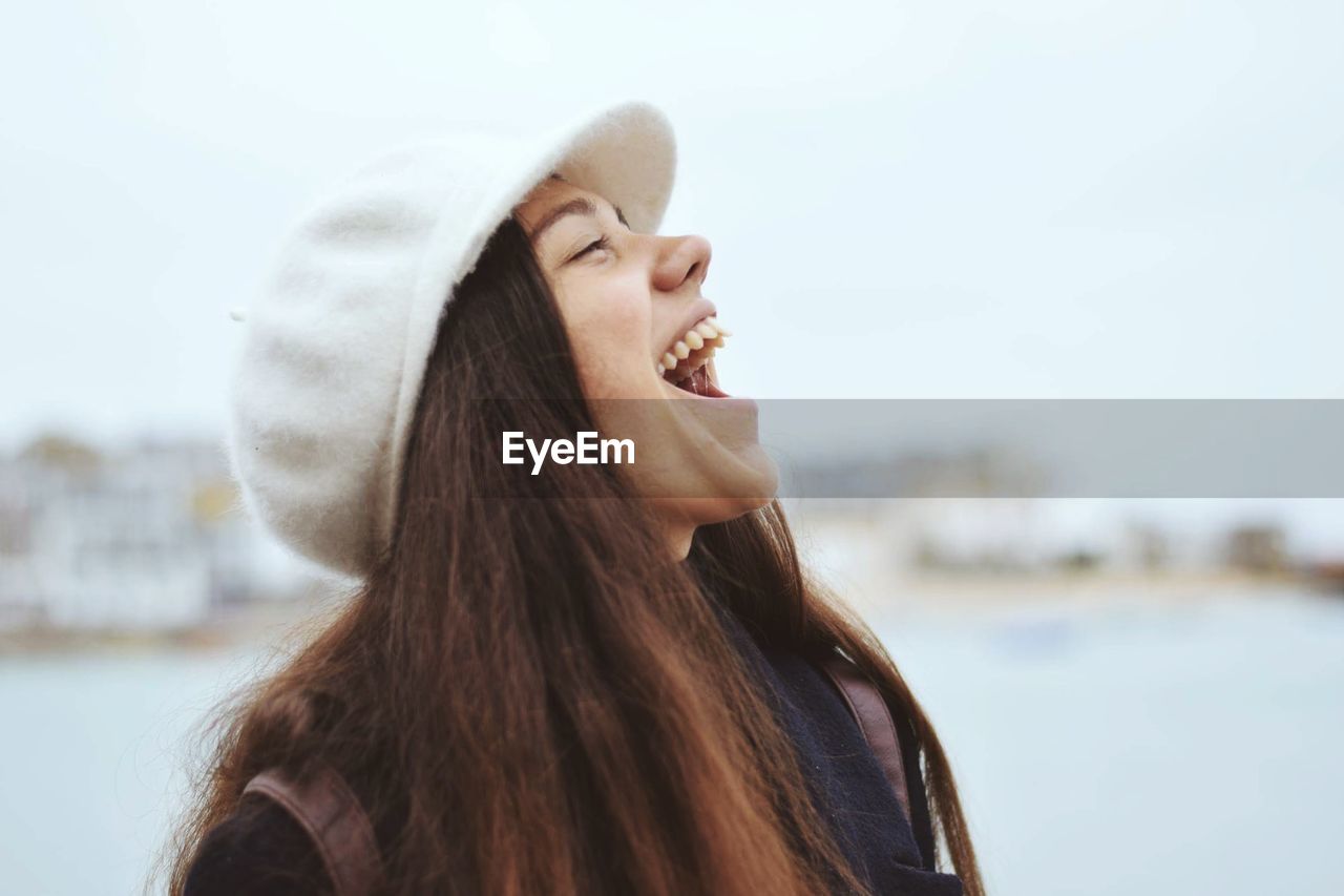 Woman laughing against sky