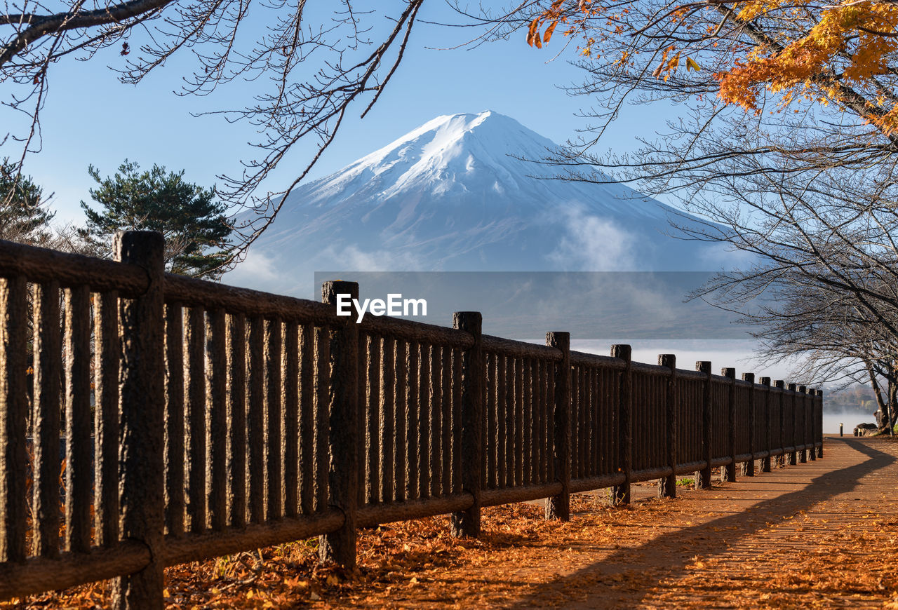 Scenic view of fence and snowcapped mountains against sky