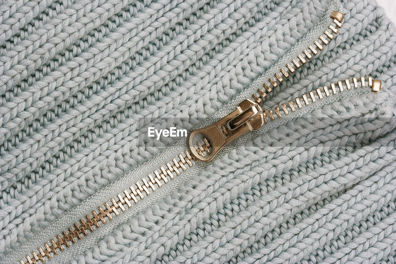 Close-up of zipper on white sweater