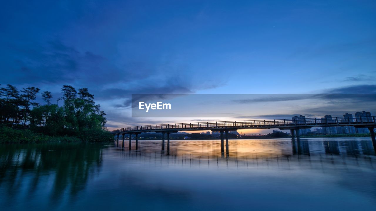 Bridge over river against blue sky at dusk