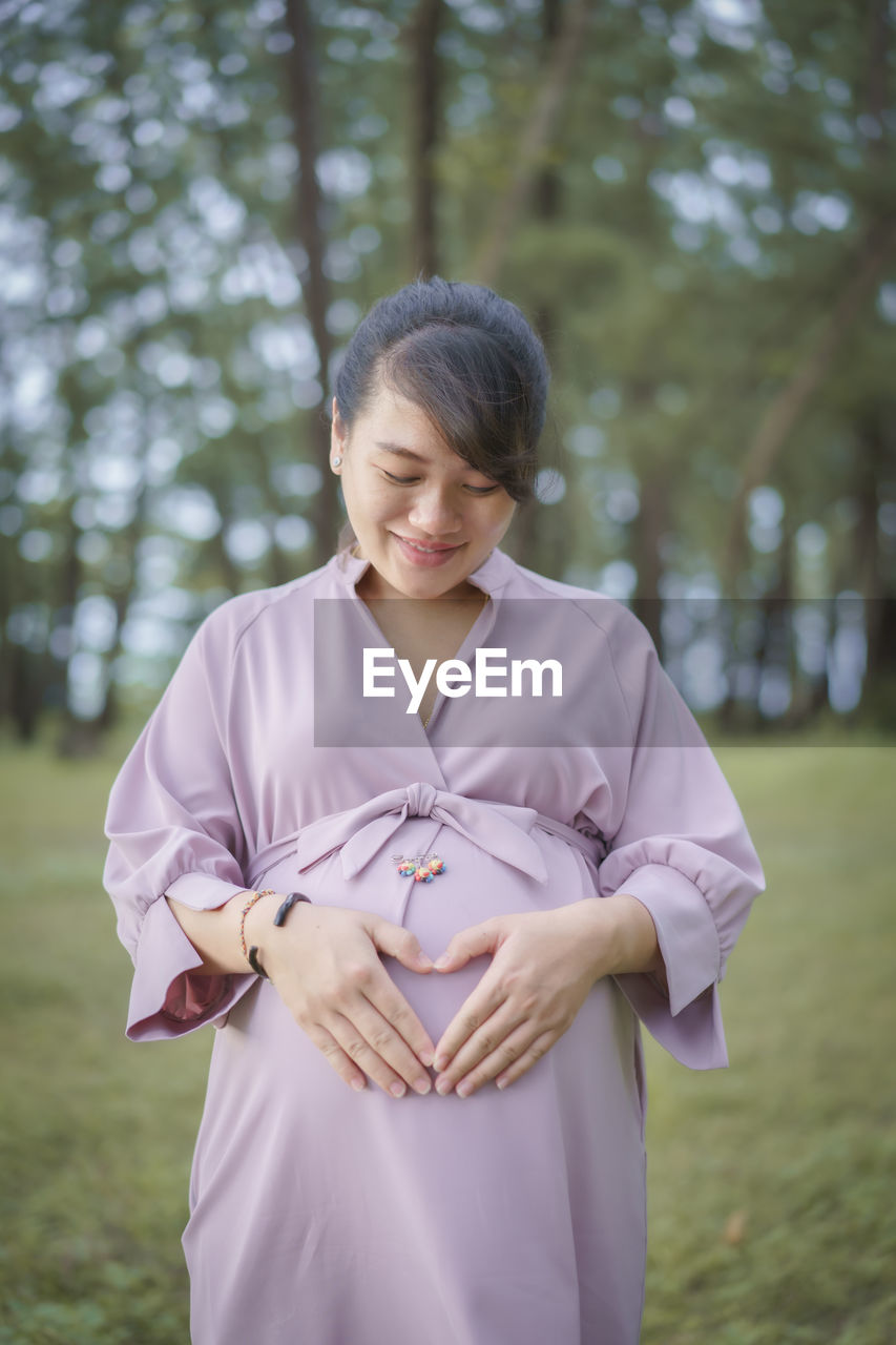 Beautiful pregnant woman standing in park