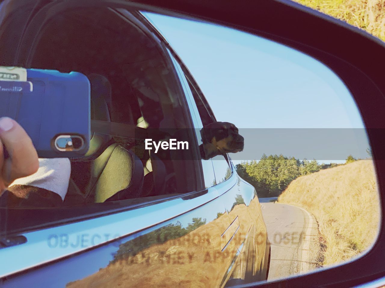 REFLECTION OF MAN IN CAR MIRROR