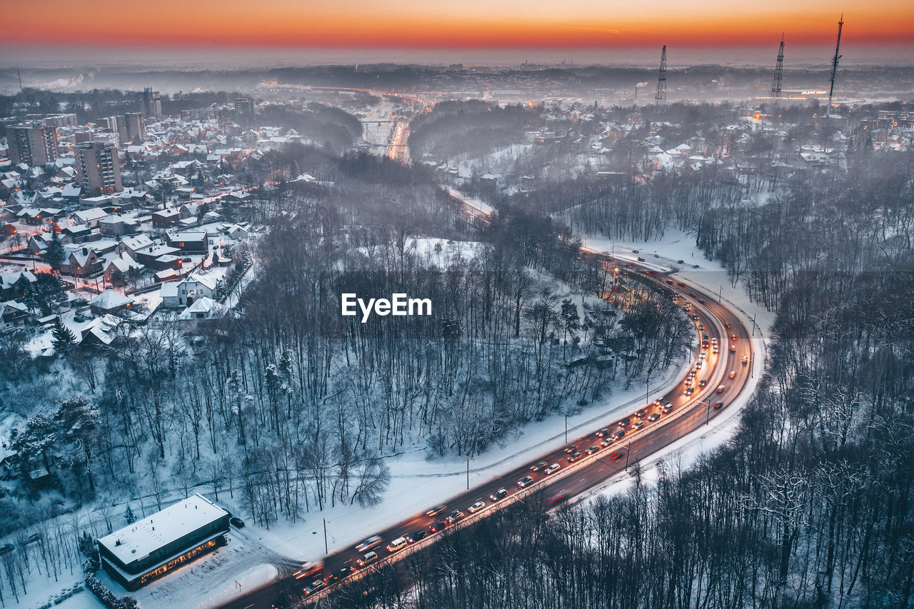 Aerial view of vehicles on road amidst snow covered landscape during sunset