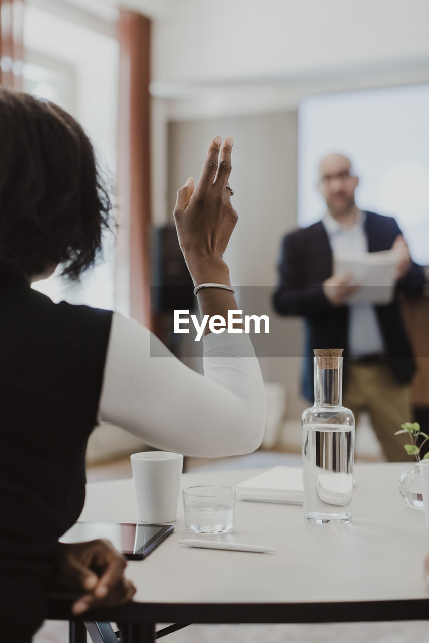 Female entrepreneur asking question while male colleague giving presentation at education class