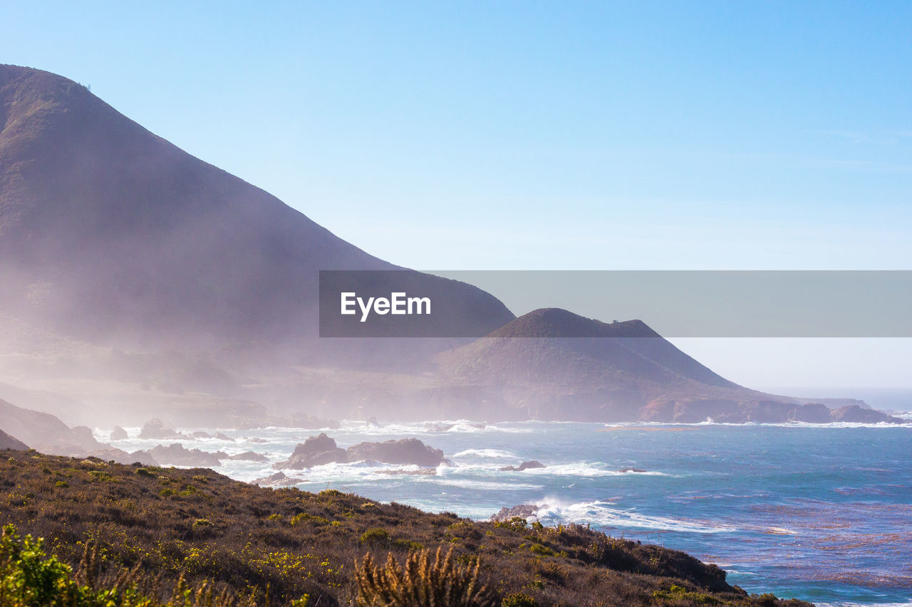 Scenic view of sea and mountains against clear sky