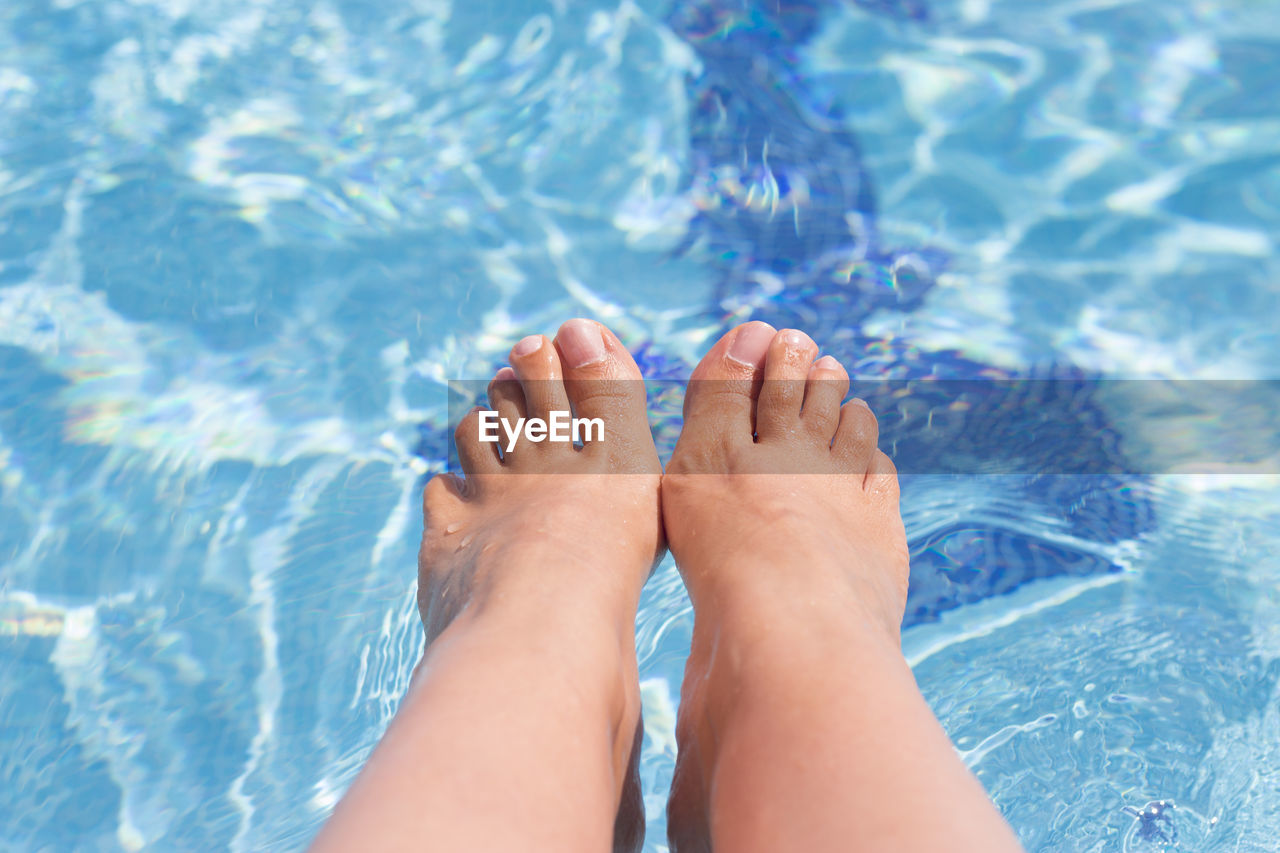 Low section of woman relaxing in swimming pool