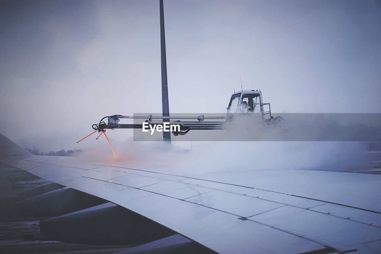 De-icing of airplane against cloudy sky