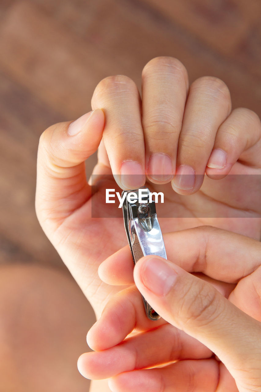 Cropped hands of woman cutting nails with clipper