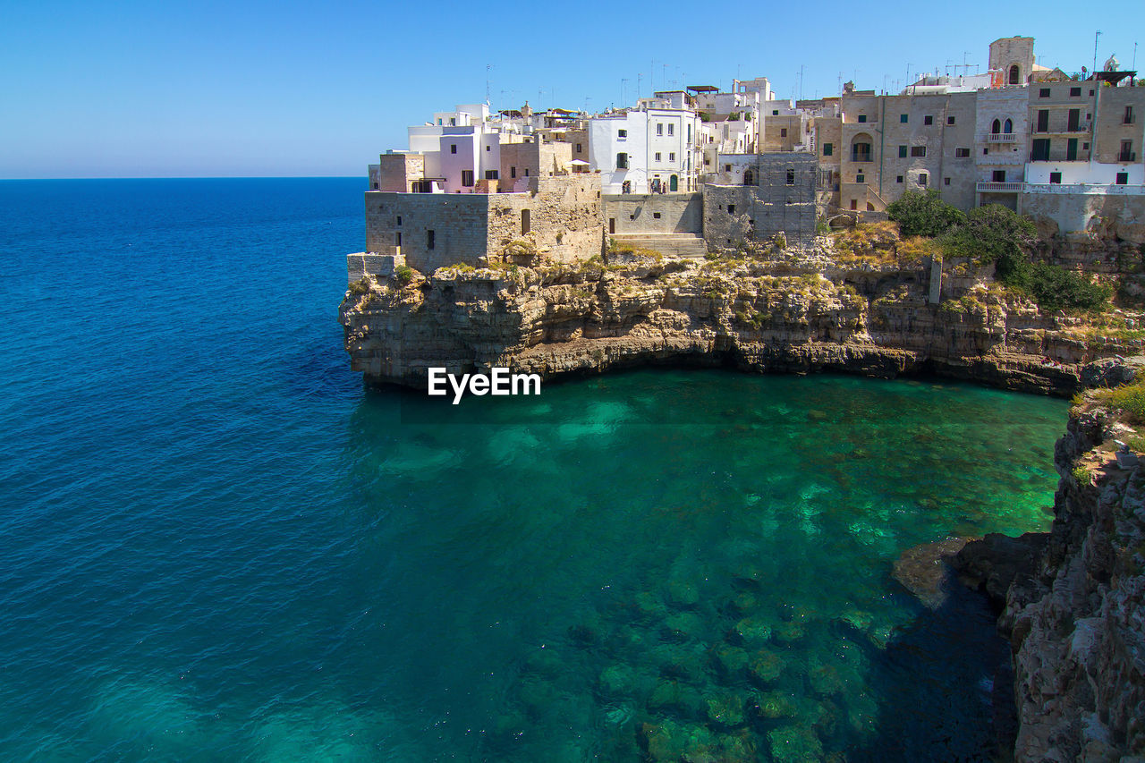 Buildings at sea shore against clear sky