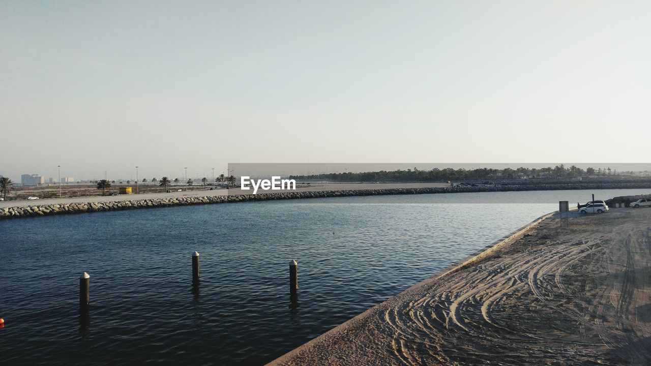 DISTANT VIEW OF HARBOR BY SEA AGAINST CLEAR SKY