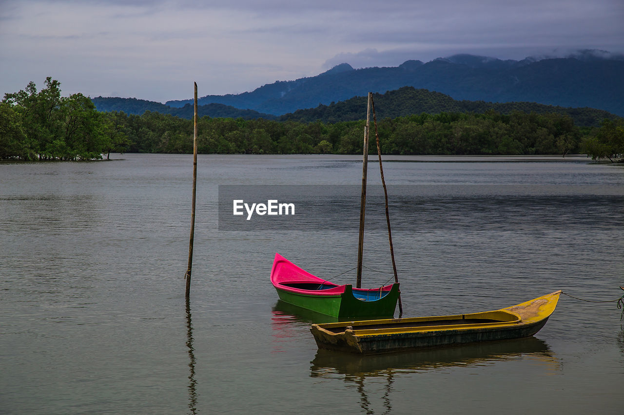 SAILBOAT MOORED IN LAKE AGAINST SKY