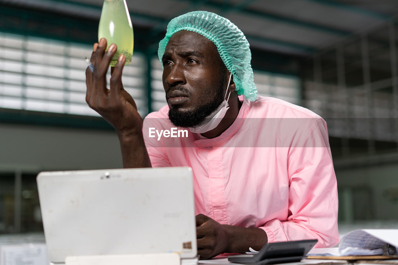 YOUNG MAN USING MOBILE PHONE IN LAPTOP