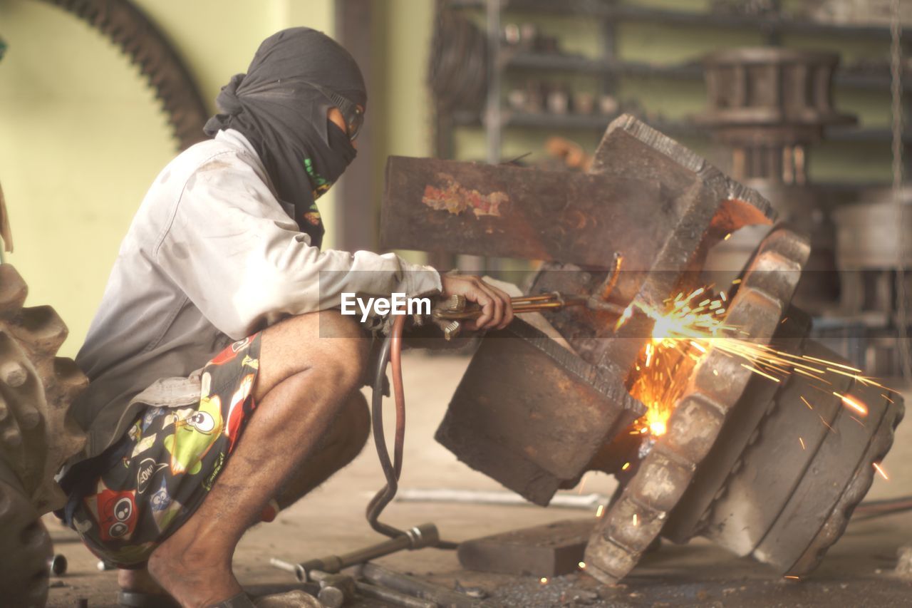 Man welding machinery in workshop