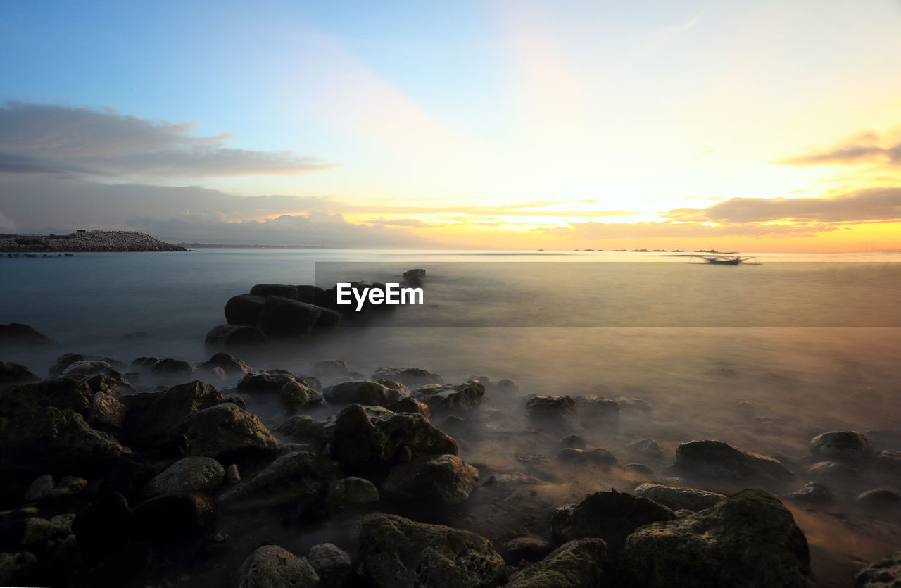 sky, sea, water, sunset, beauty in nature, land, scenics - nature, ocean, beach, nature, rock, cloud, horizon, coast, shore, body of water, tranquility, wave, dawn, horizon over water, sun, tranquil scene, seascape, sunlight, environment, no people, idyllic, evening, coastline, motion, wind wave, outdoors, landscape, travel destinations, bay, dramatic sky, travel, sand, twilight, long exposure