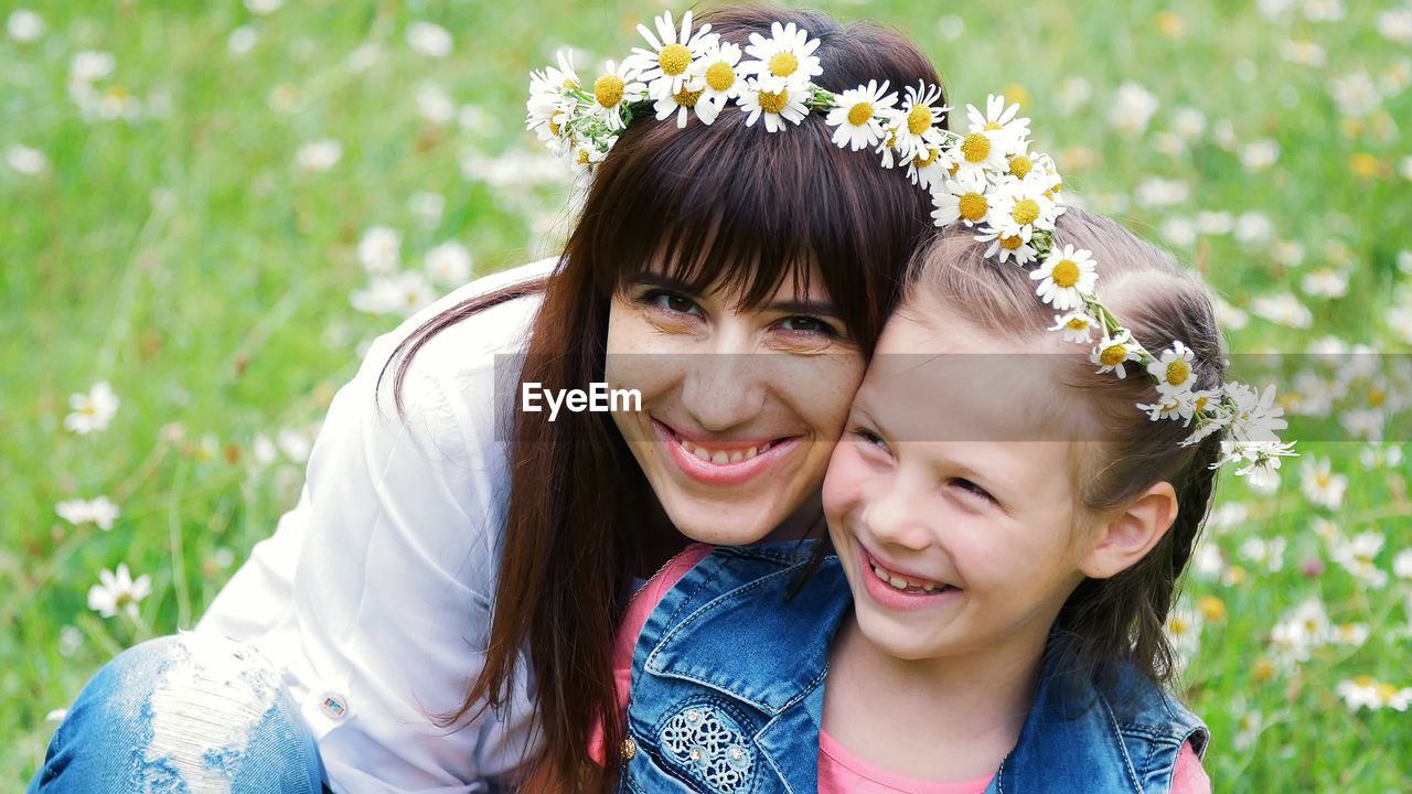 Amidst a chamomile lawn, a young woman, a brunette and a girl of seven, mother and daughter