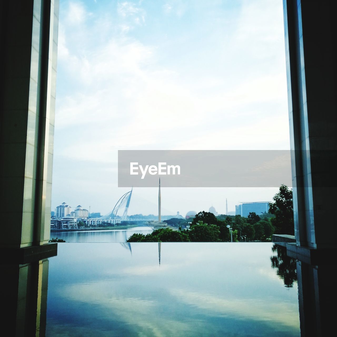 View of city at waterfront against cloudy sky