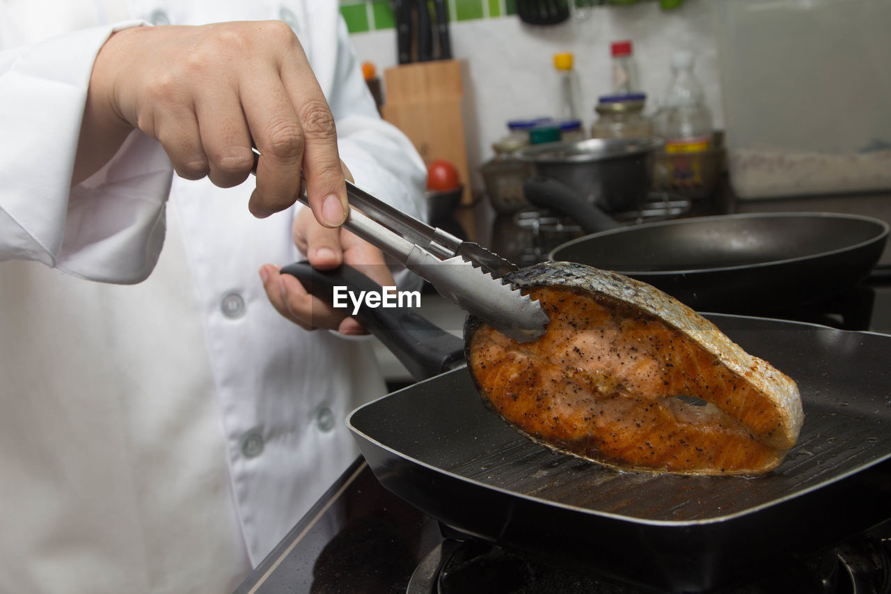 MIDSECTION OF MAN PREPARING FOOD AT KITCHEN