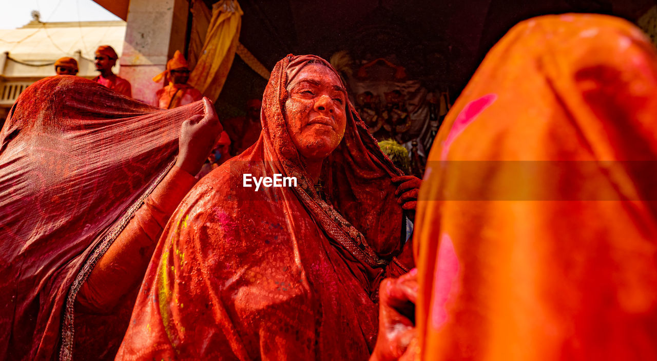 Low angle view of woman wearing sari with powder paint standing outdoors