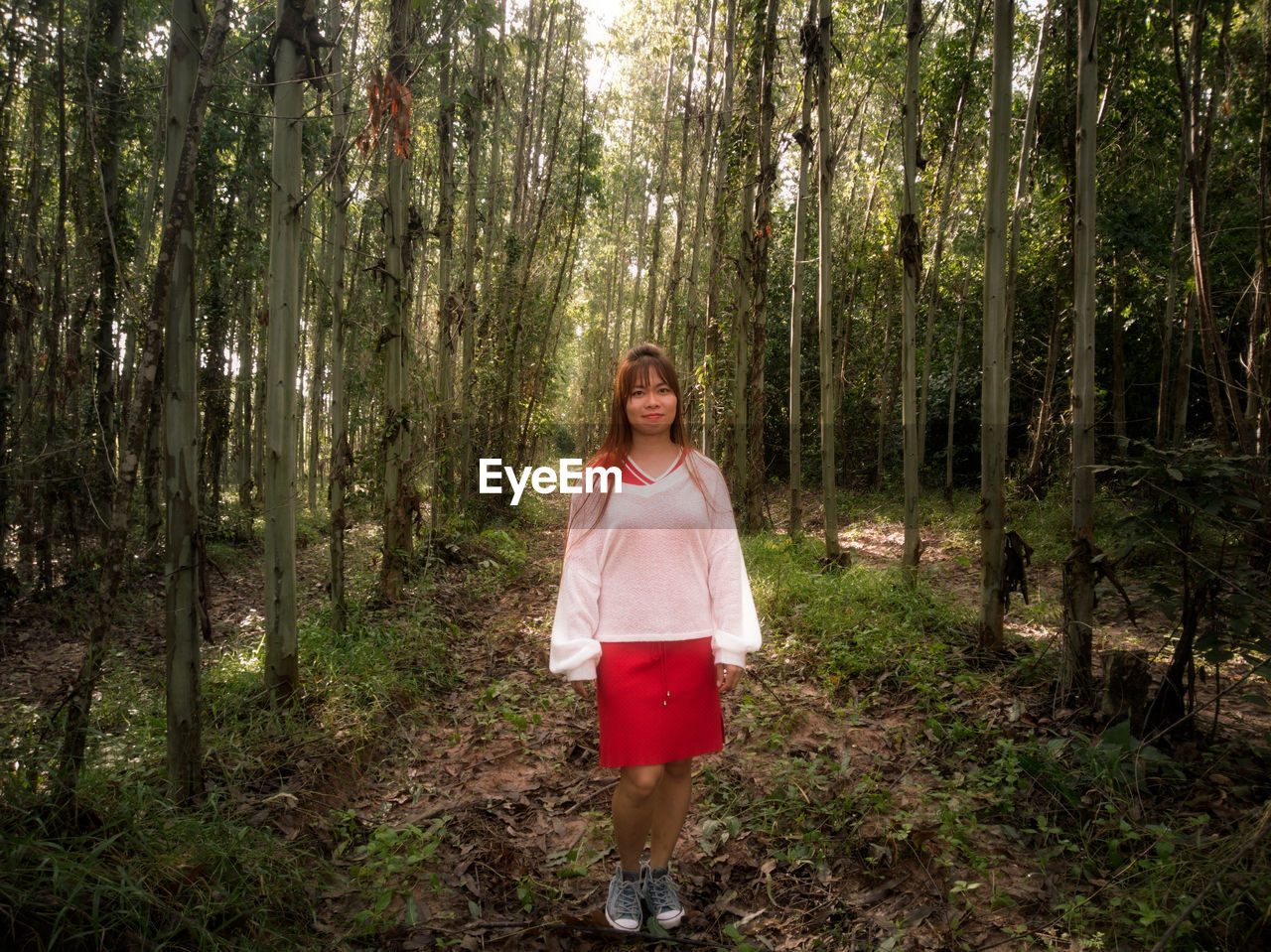 Portrait of mid adult woman walking on field amidst trees in forest