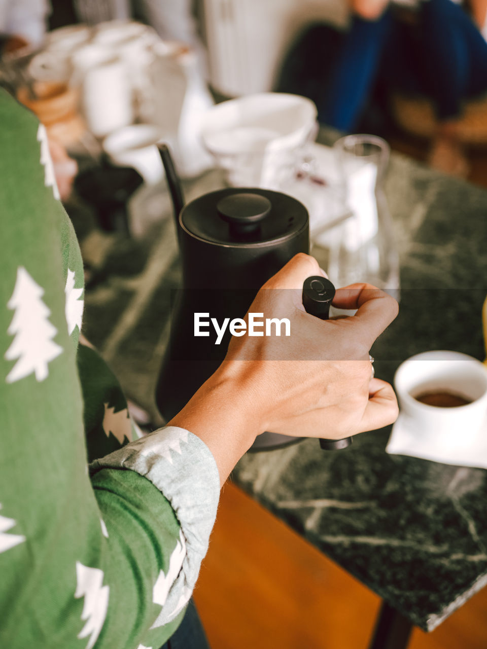 Midsection of woman having coffee at table