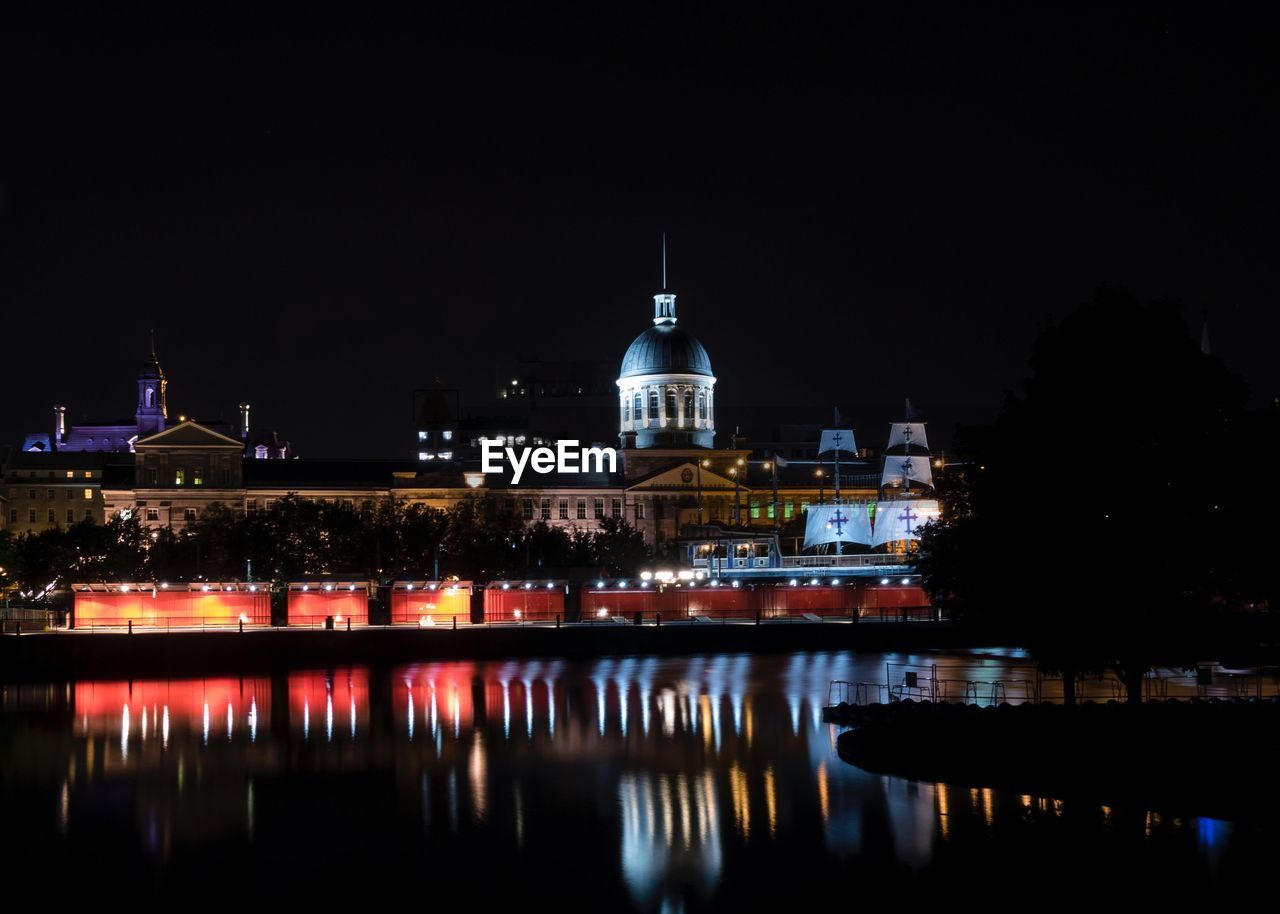 Reflection of illuminated building on river in city at night