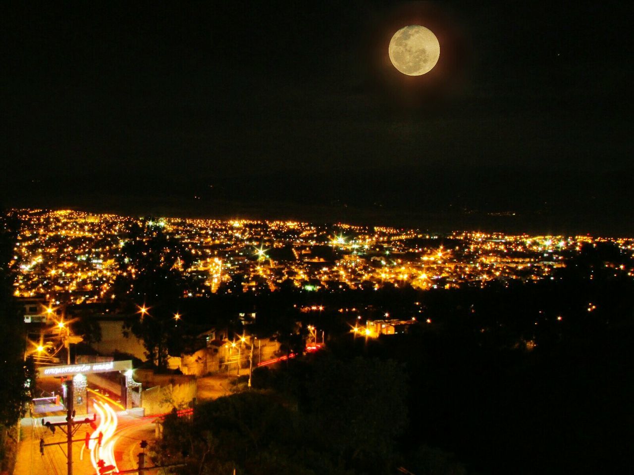 Idyllic view of majestic full moon on illuminated cityscape at night