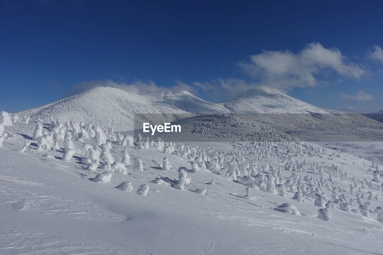 Scenic view of snow covered mountains against blue sky