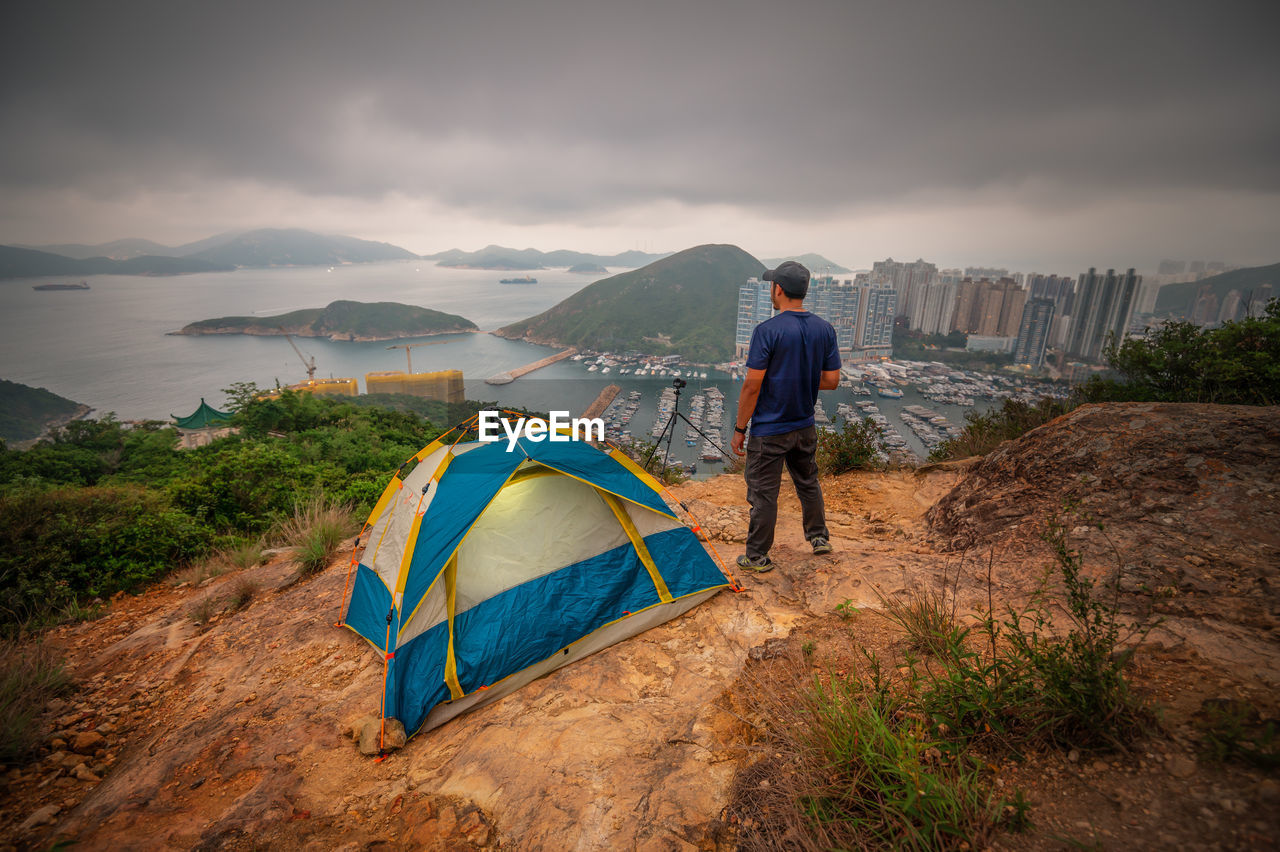 Man traveler taking photo on top of mountains near of tent camping